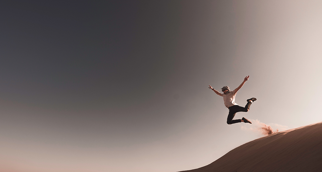 a person jumping off a dune