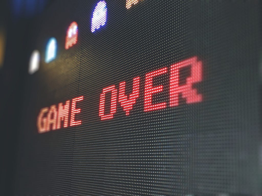 Zoom em ecrã com as palavras Game Over em fonte pixelada e fantasmas coloridos