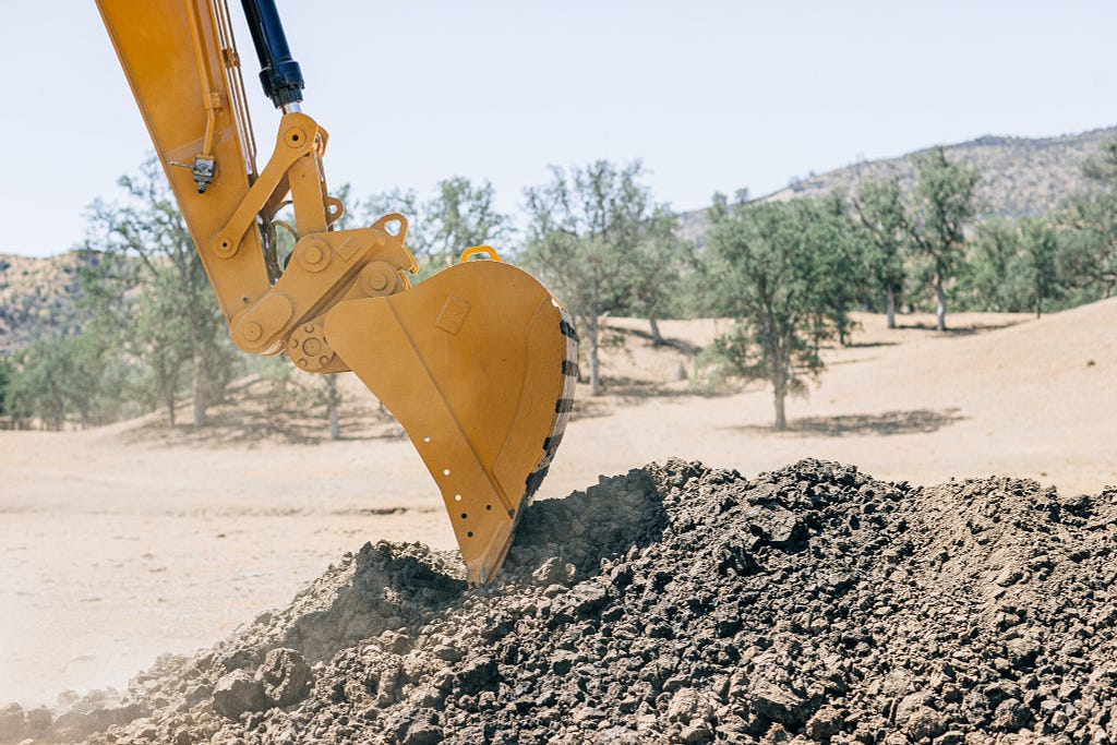 Picture of a back hoe with a bucket, digging up dirt.