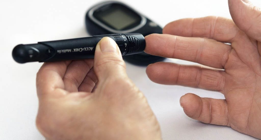 Man testing blood sugar level after intermittent fasting