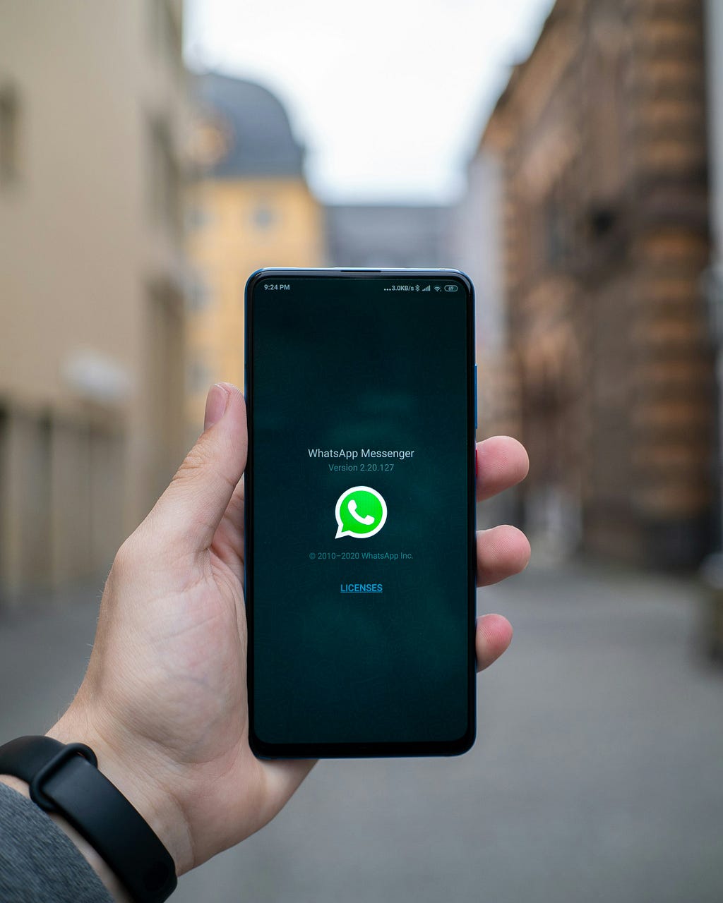Hand holding a black phone with whatsapp logo on the screen