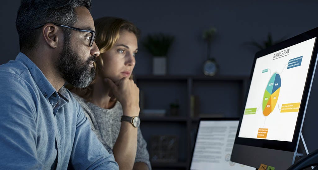 Boss working late alongside employee at office