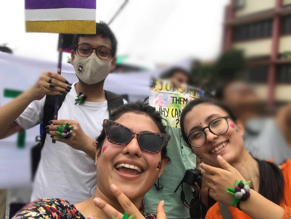 An image showing me and my two colleagues at Nepal Pride Parade 2022 showing our pride accessories.