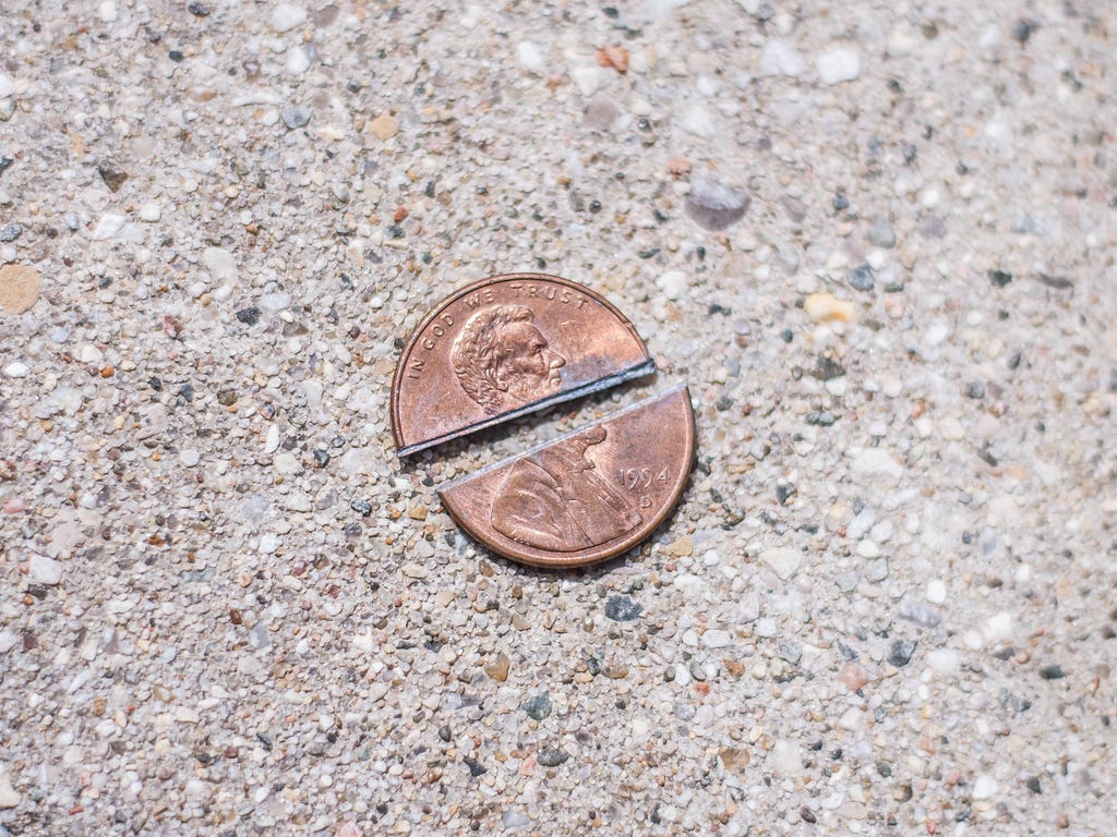 Penny split in two pieces on a concrete background