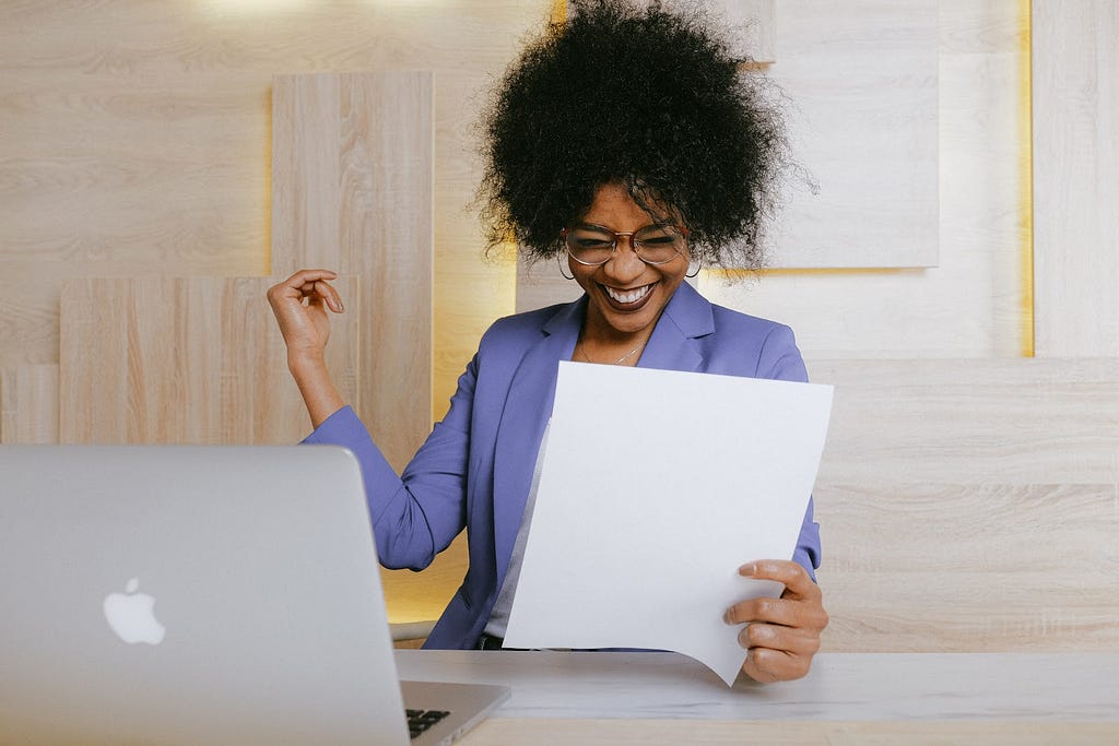 A woman smiling and holding a business document.