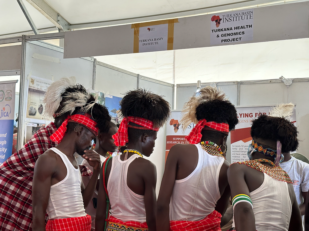 Attendees of the 2023 Turkana Cultural Festival learning about the Turkana Health and Genomics Project and Variant Bio’s role in the study at a booth inside the Ekaales Cultural Center.