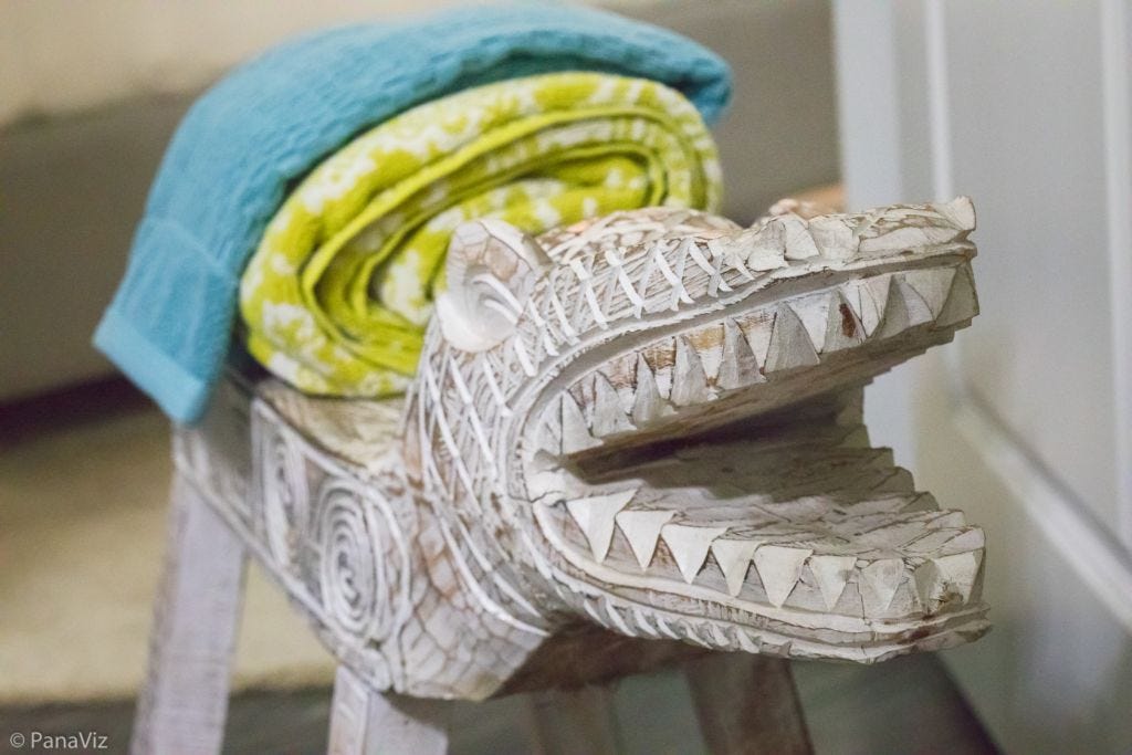Wooden stylized dog bath stool with lime green and blue towels stacked on top.