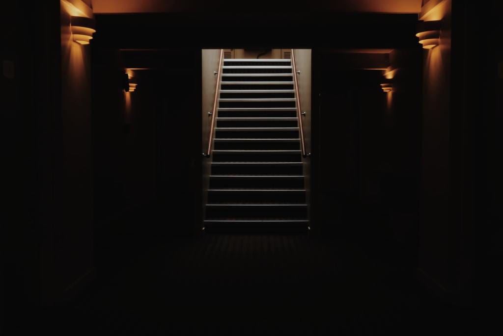Stairway leading up from the darkness. Photo by Ginevra Austine on Unsplash