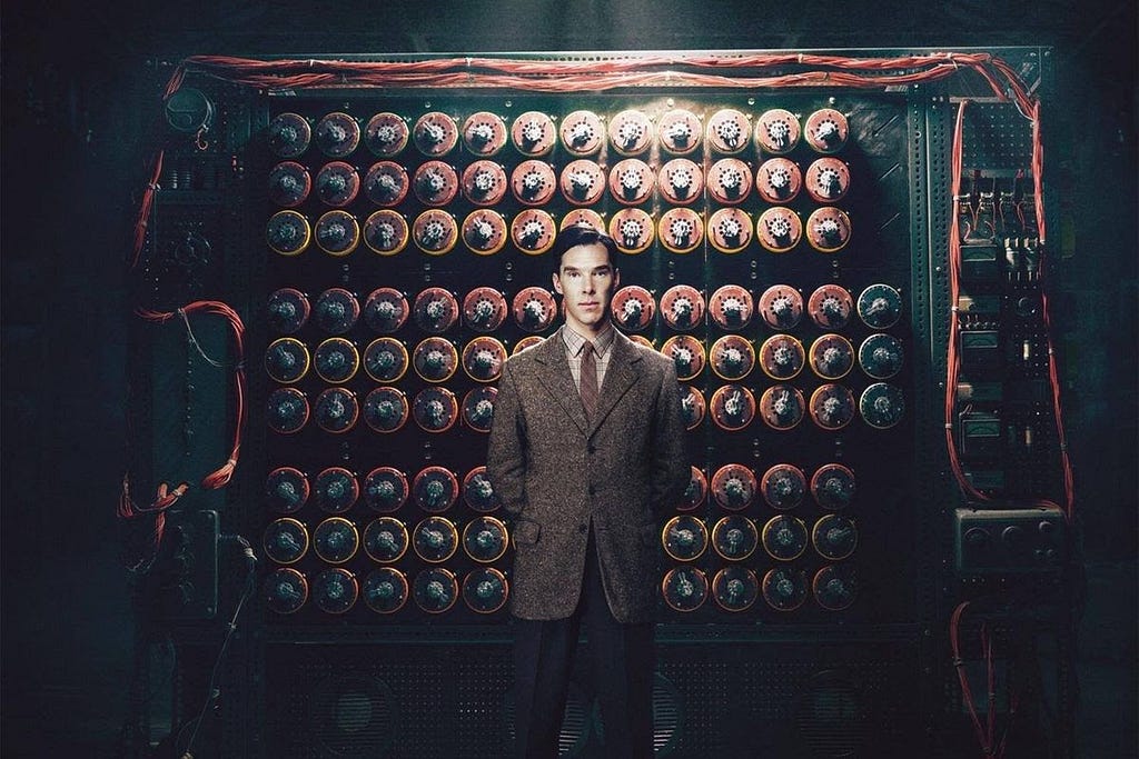 A movie scene shot of actor Benedict Cumberbatch as Alan Turing standing in front of the Imitation Game movie rendition.