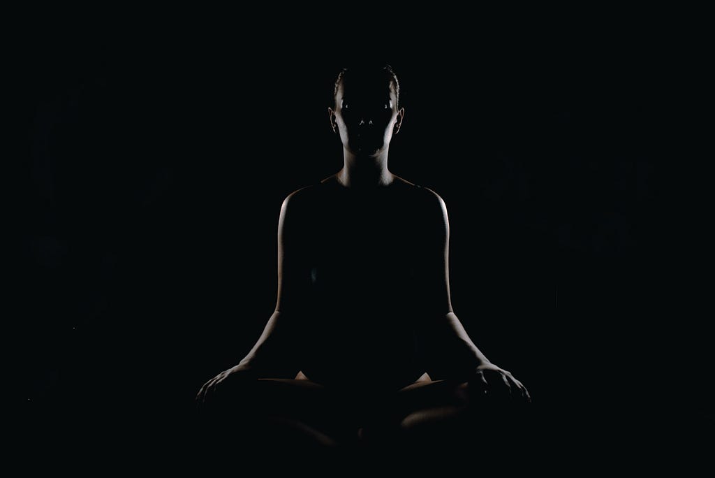 darkened photo of a person meditating