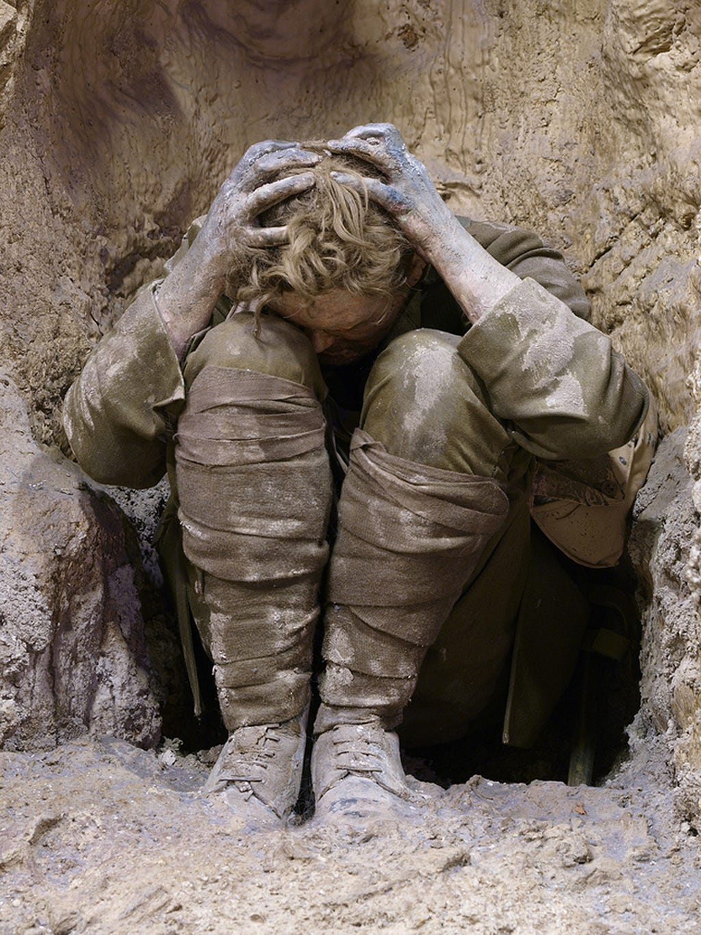 Image of a soldier from World War 1, curled up in shock inside  a trench.