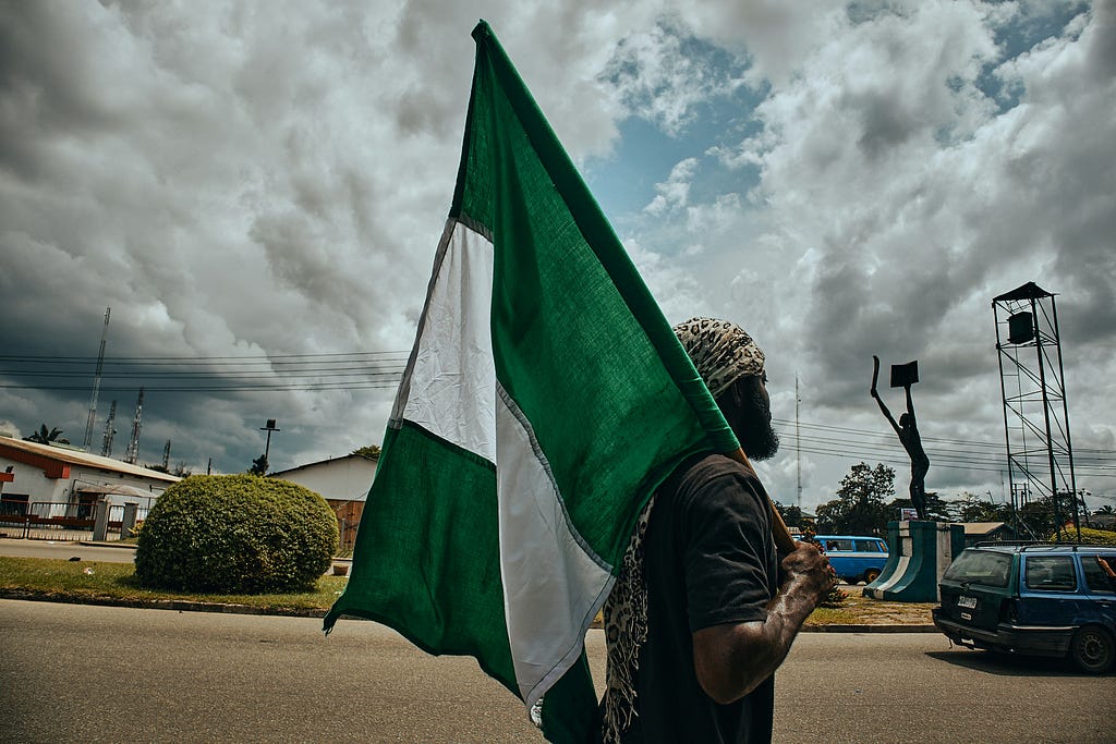 A Nigerian man holding his nation’s flag in one of its public squares