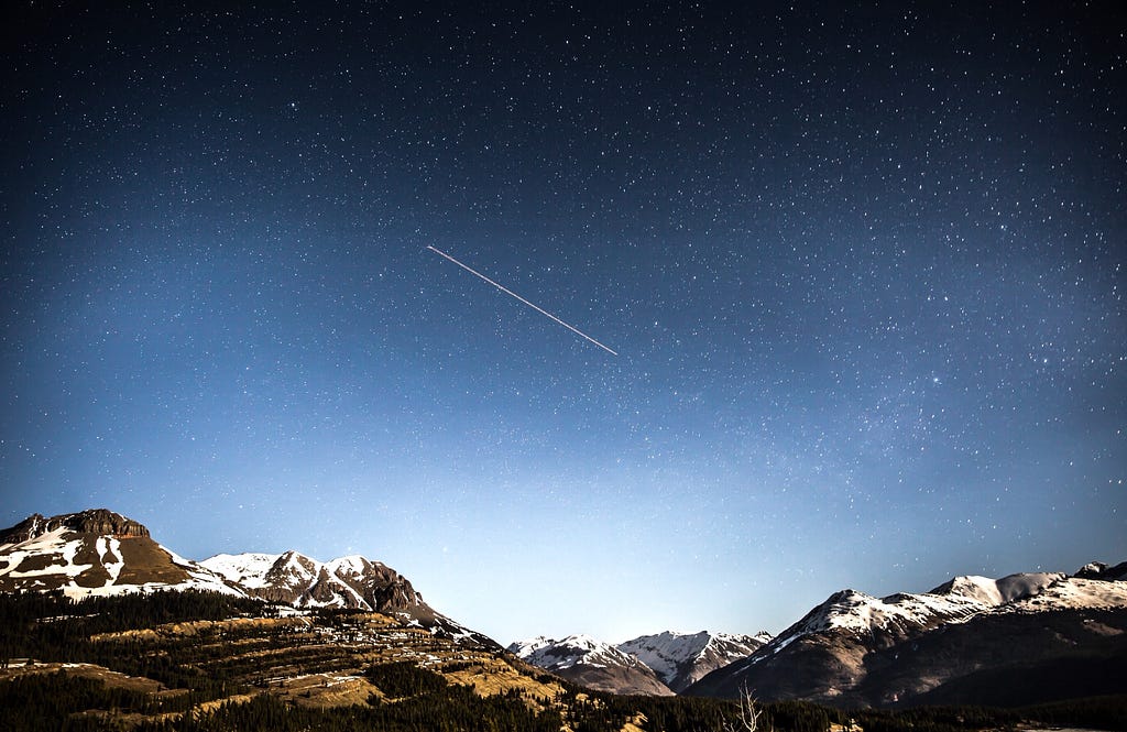 A shooting star over mountains.
