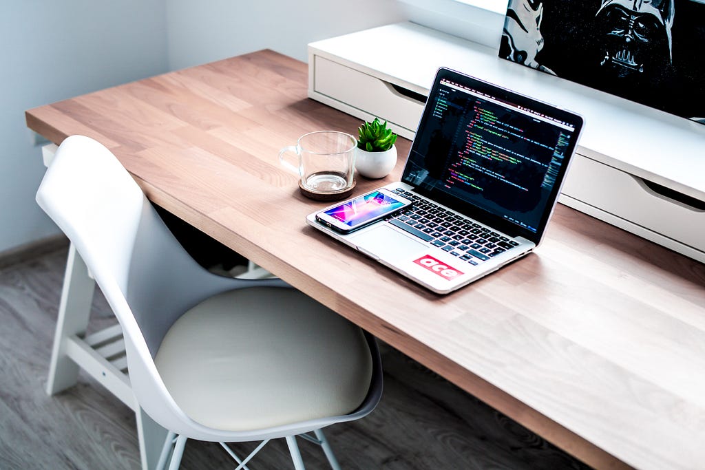 Learning programming: Laptop and phone on an office table with a study chair.