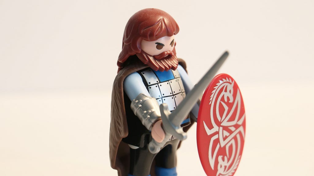 A Playmobil figure dressed as a knight with armour, sword and shield.