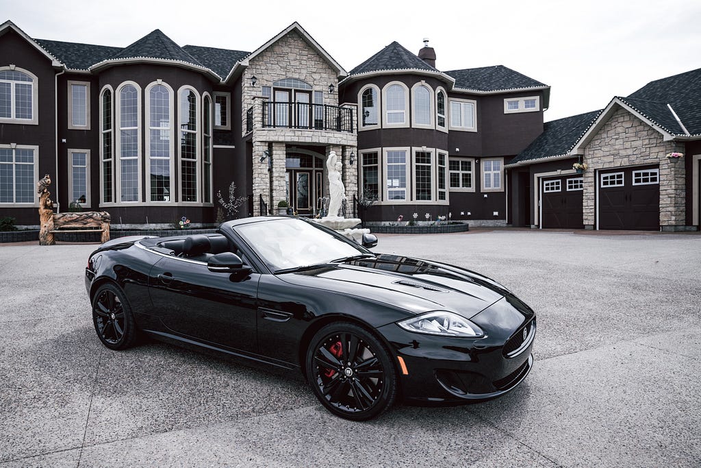 A big villa in black and dark brown paint and a black car standing in front of it. It represents the lavish lifestyle of wealthy people.