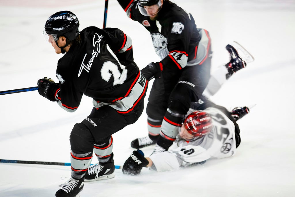 Two hockey players collide in pursuit of the puck