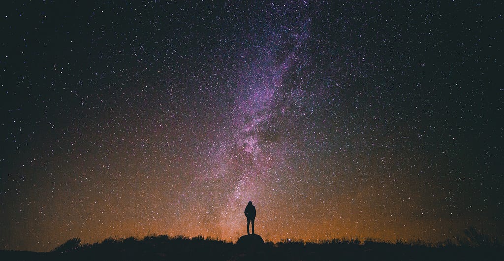 A person standing and watching the sky full of stars.