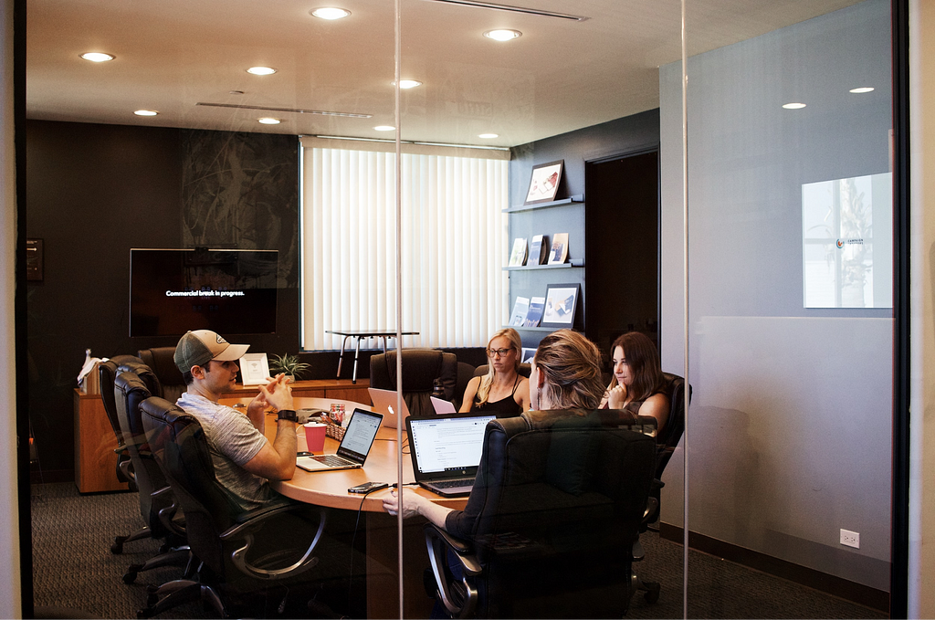 A board room with a team of men and women discussing digital product work.