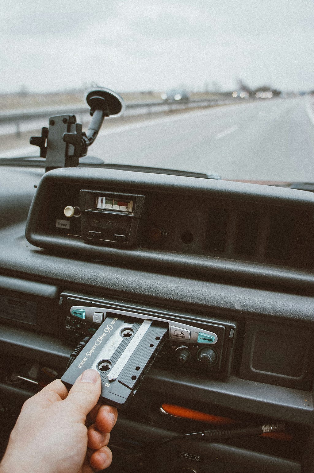 A hand placing a cassette into a car stereo