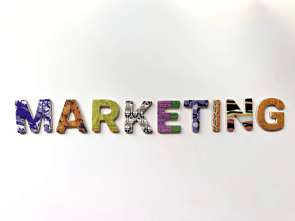 Decorative magnetic letters on a white surface spelling the word “Marketing.”