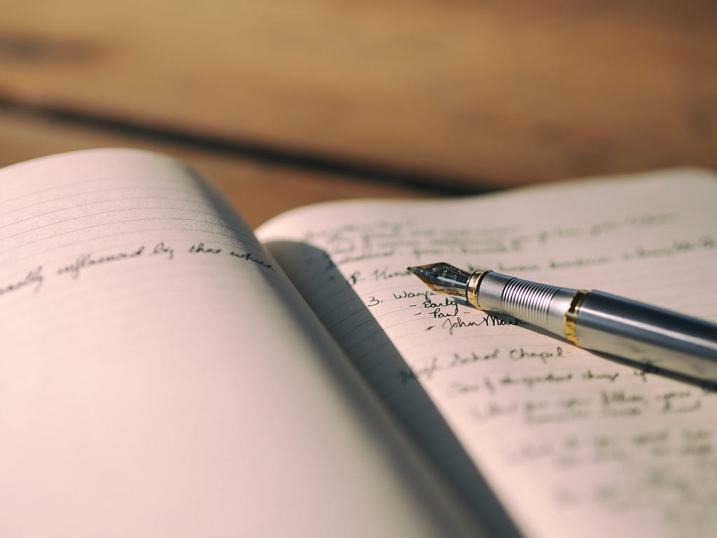 A photo of an open journal with an old-fashioned pen and handwriting.