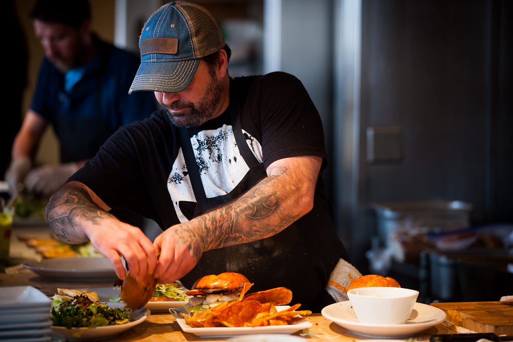 man eating a hamburger, salad, and fries