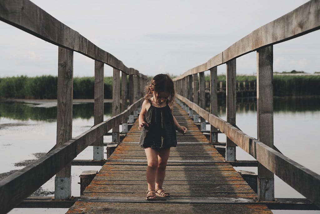 A girl walking on a narrow bridge.