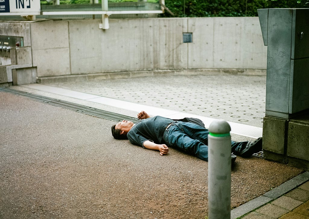 A man laying on a walkway outside
