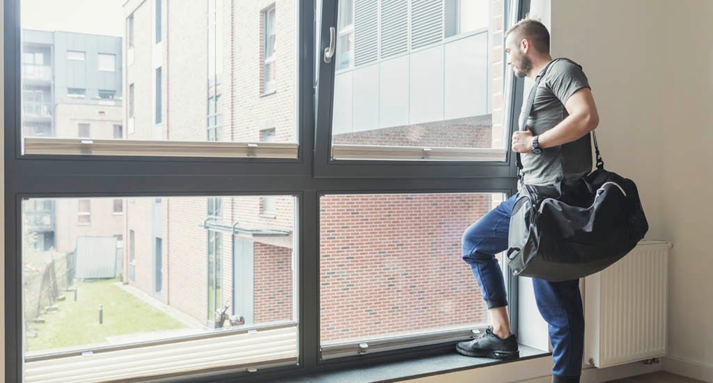 Entrepreneur with gym bag looking through a window early in the morning