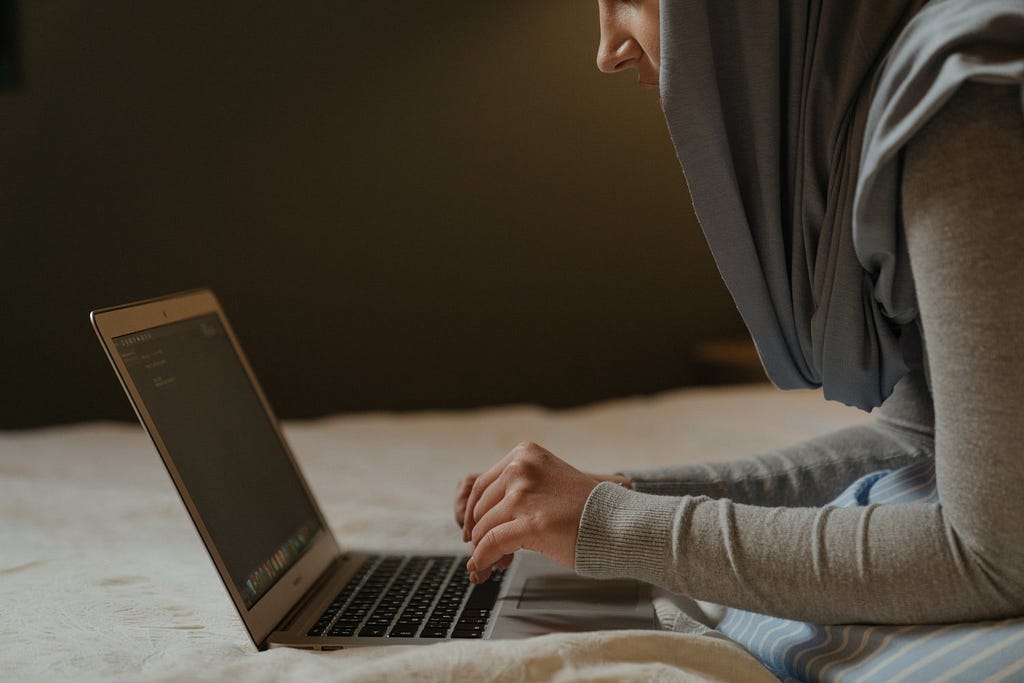 Photo of a woman wearing a hijab working on a laptop