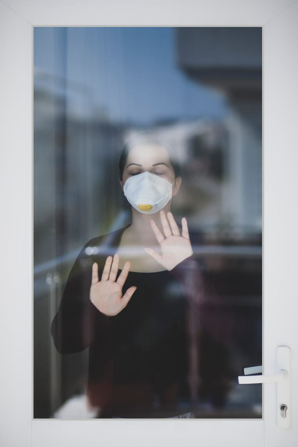 Photo of woman with face mask behind glass wall. Photo posted on Dr. James Goydos 2021 article about mask requirements and debate between Dr. Fauci and Rep. Jordan