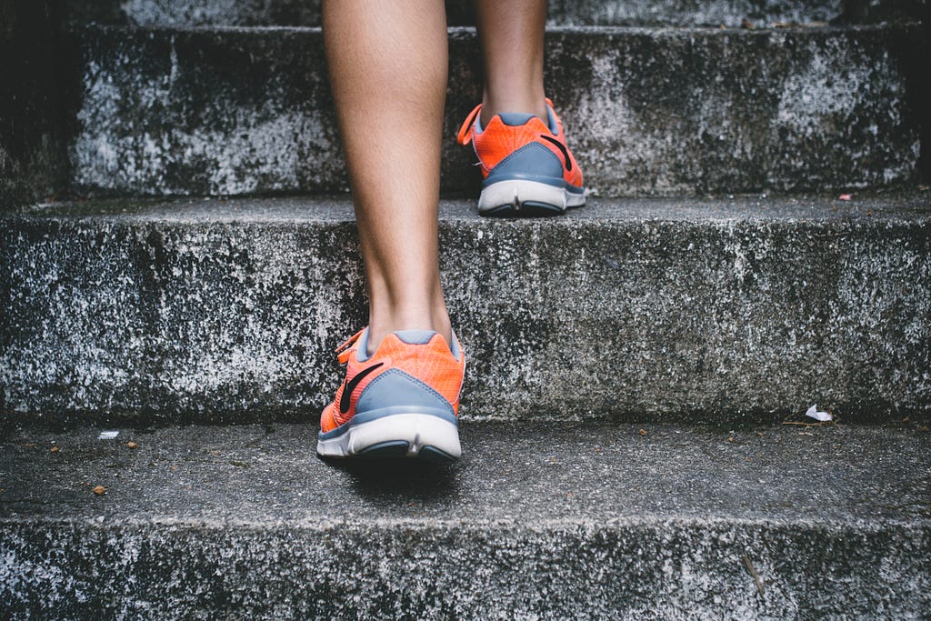 A woman climbing stairs, taking one step at a time.