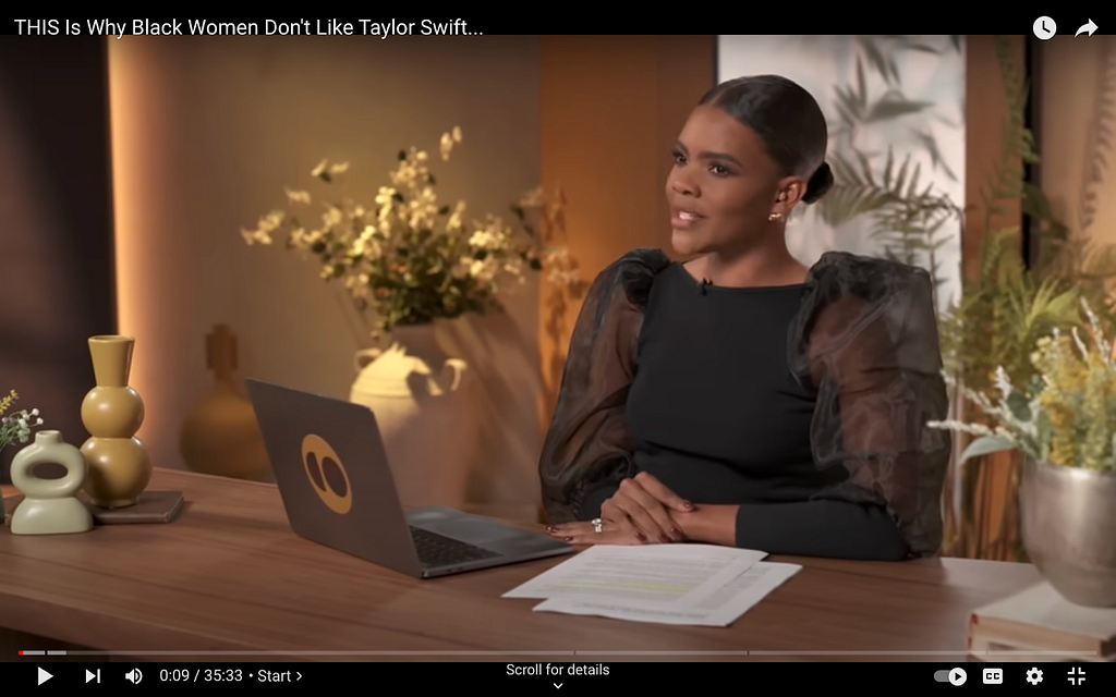 A screenshot from Candace Owens’s show on The Daily Wire. She wears a black dress with a boat neckline. The dress has dramatic puff sleeves that are long. They are made of a gauzy, sheer black fabric that you can see her bare arms through. This sheerness ends a bit after the elbow and the fabric becomes opaque again.