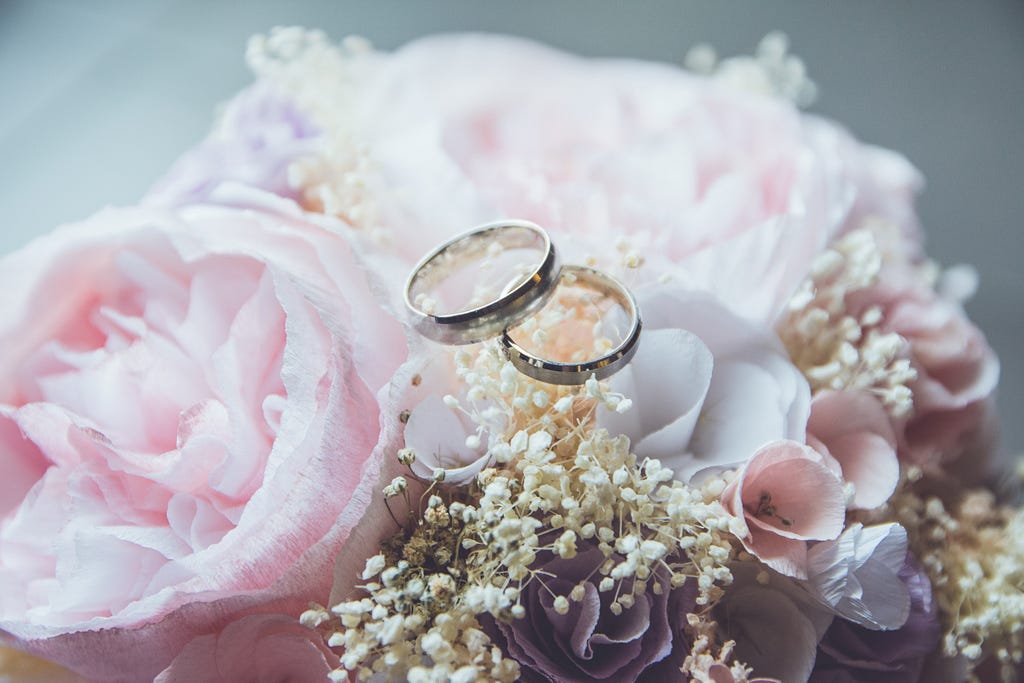 Two rings on a beautiful banquet of flowers,signifying the marital union.