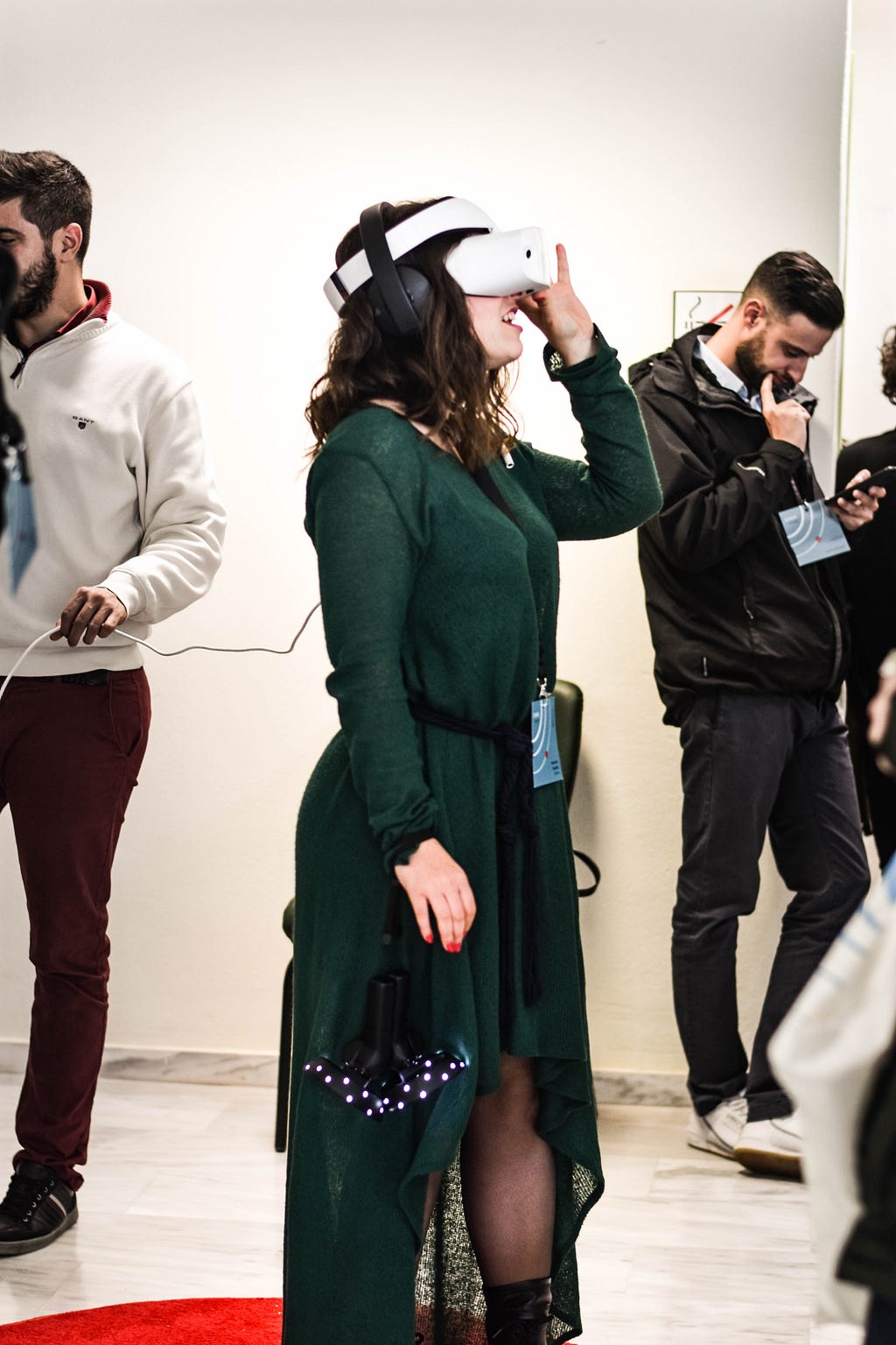 young woman wearing a long green dress wearing a VR headset in a group of other young people
