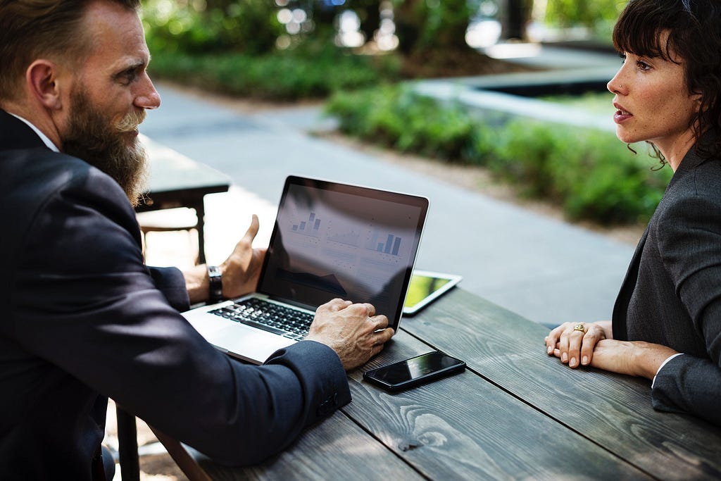 tow-people-talking-with-remotely-colleagues-video-call-computer-screen-presenting-new-business-partners — RumboMag — A virtual workplace is a work environment where employees do not physically come into an office or central location to perform their job duties