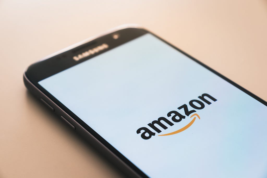 Amazon Prime When is Amazon Prime Day, Where to get Amazon Gift Cards through Amazon Surveys. Cellphone showing Amazon logo.