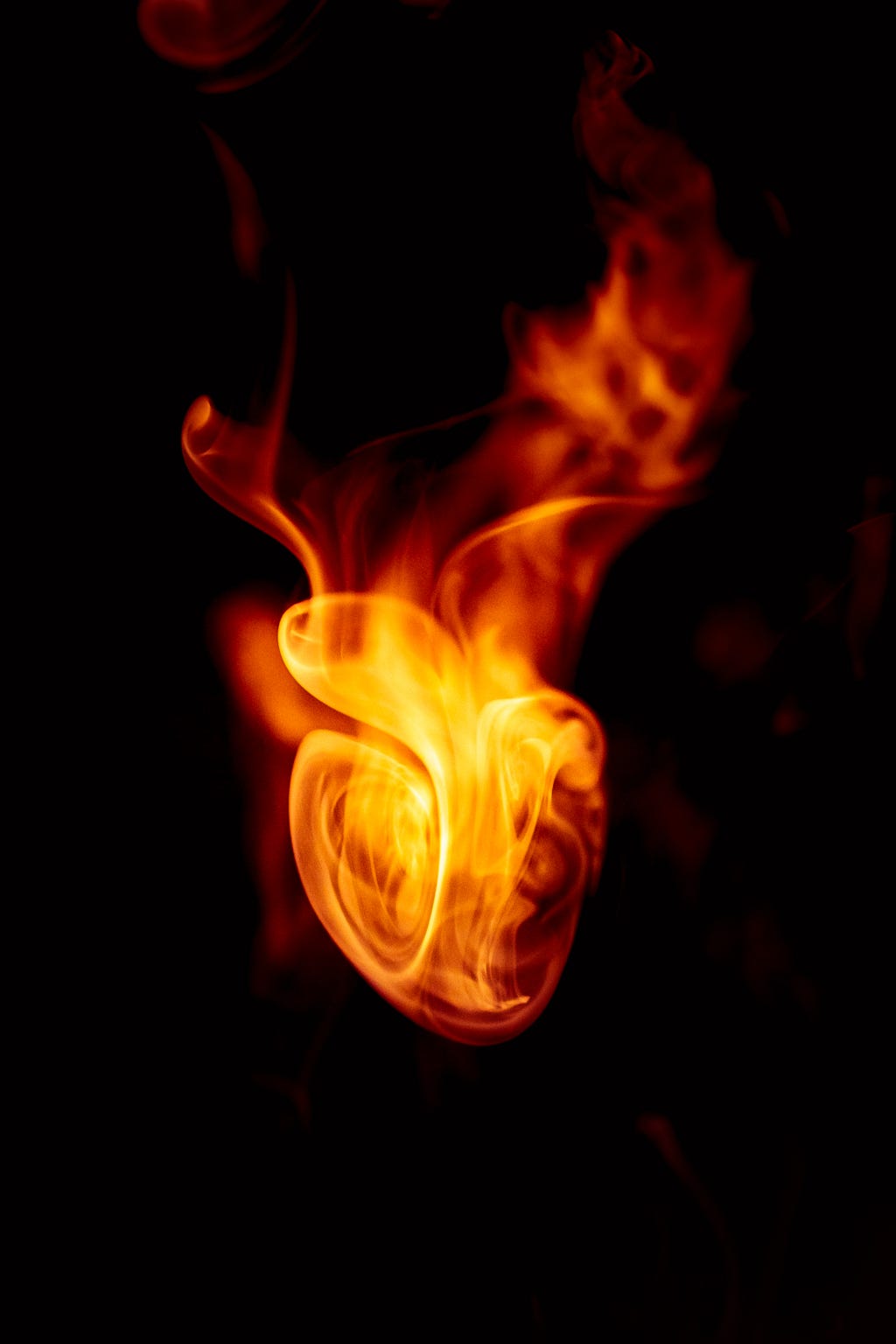 A picture of fire with a shape of a human heart, with a pitch black background
