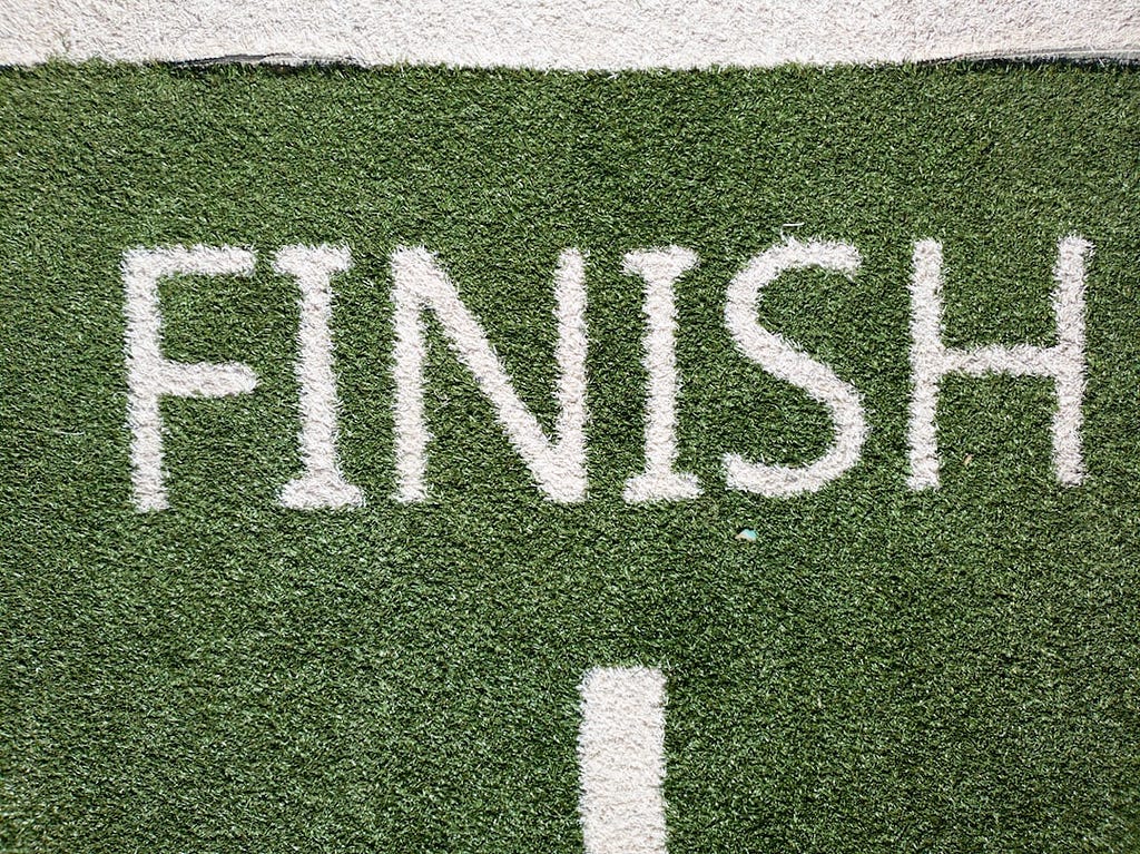 The word finish in white painted on a green lawn