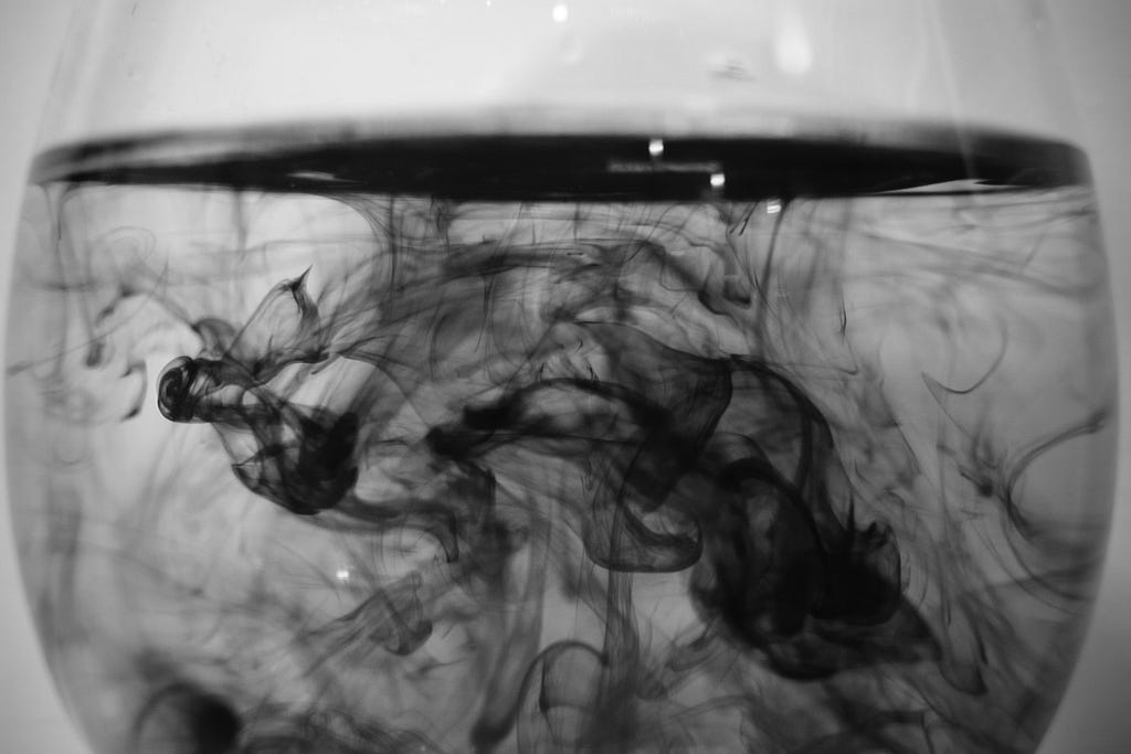 A glass of water with dissolving black ink
