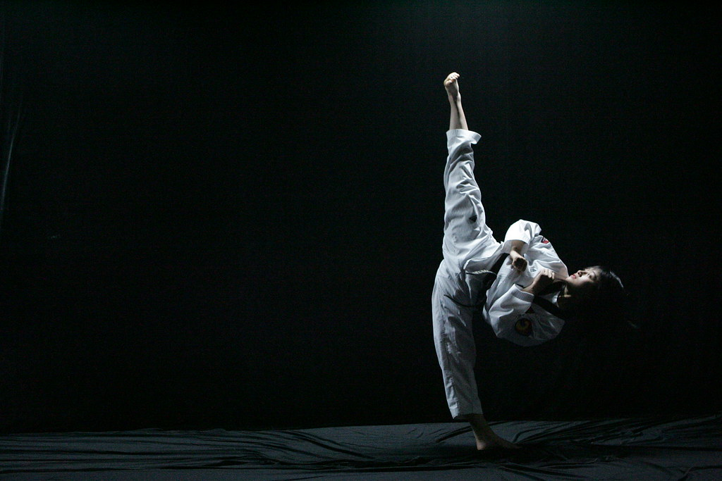 A young child practicing Taekwondo aims a kick to the sky