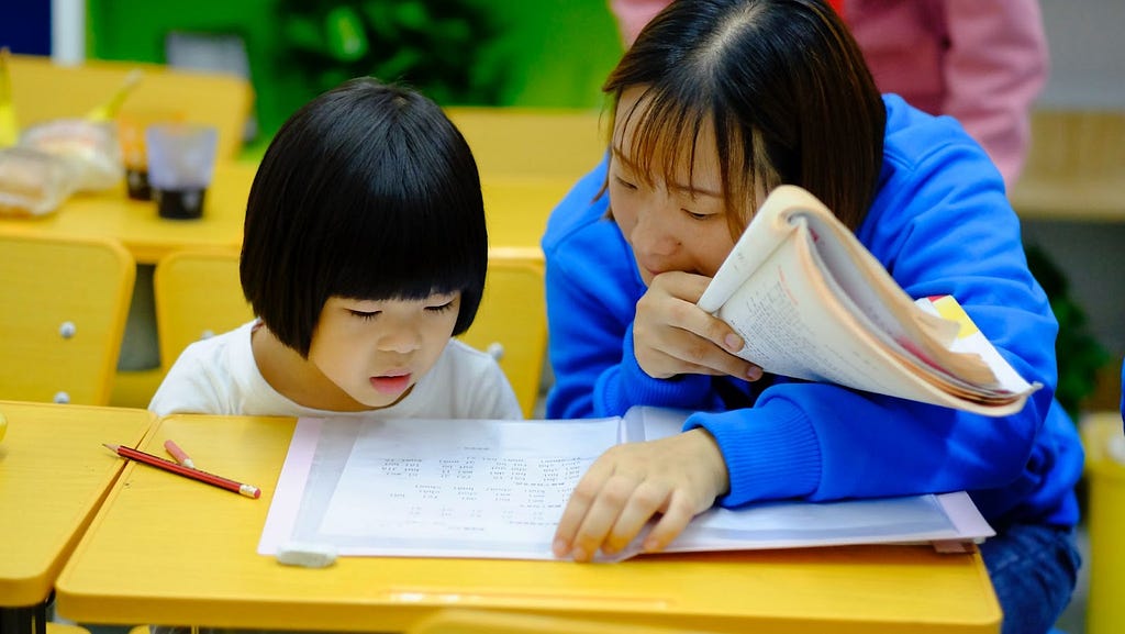 A woman and child reading in a classroom setting