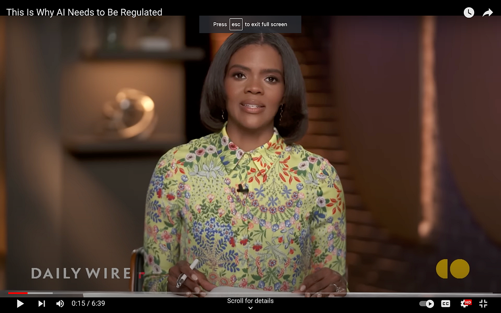 A screenshot from Candace Owens’s show on The Daily Wire. She wears a fitted, long-sleeve blouse with a riotous floral pattern. There are hints of red, deep purple, white and pink flowers with dark green leaves against a chartreuse green background.