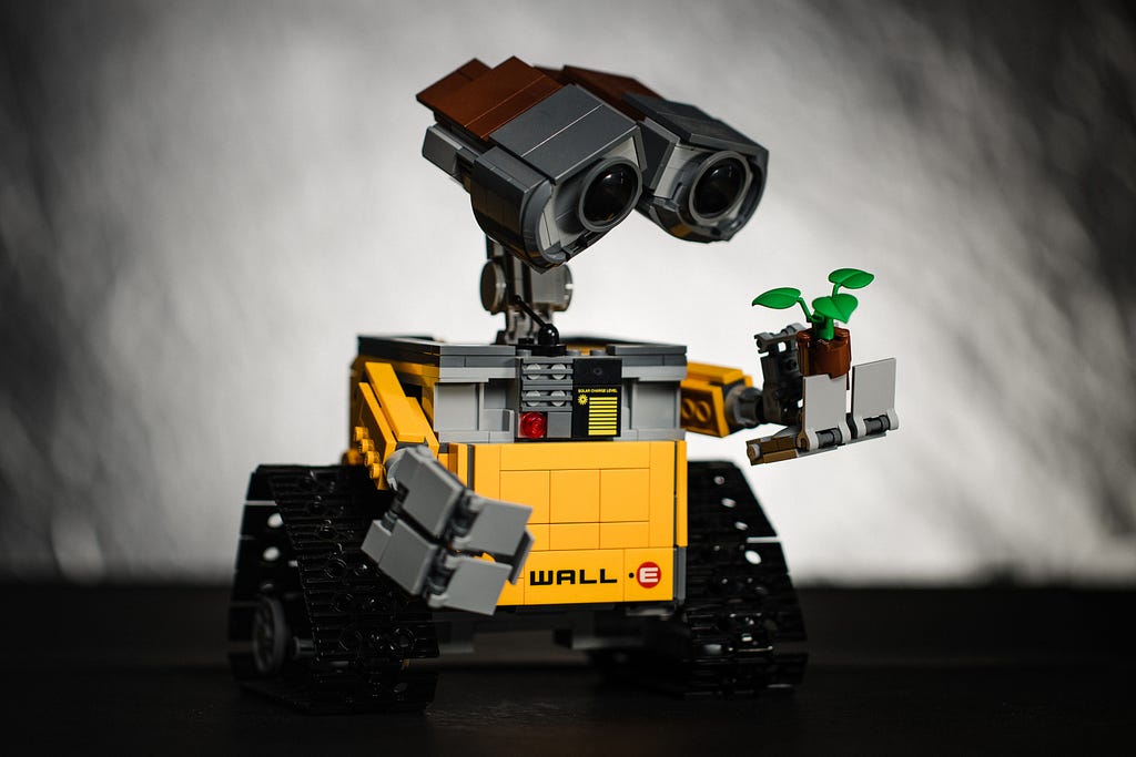 The Wall-E robot looks at a plant in its hand