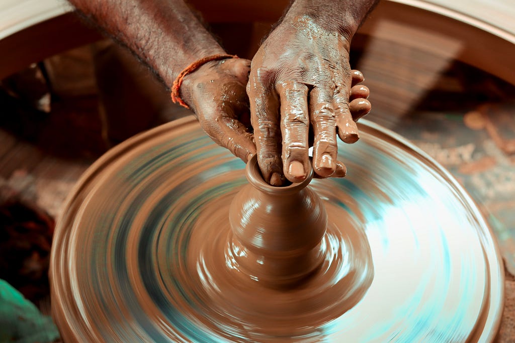 A potter molding a vessel using clay