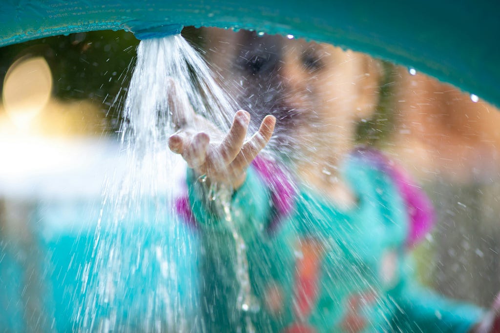 a little girl touching splashing water