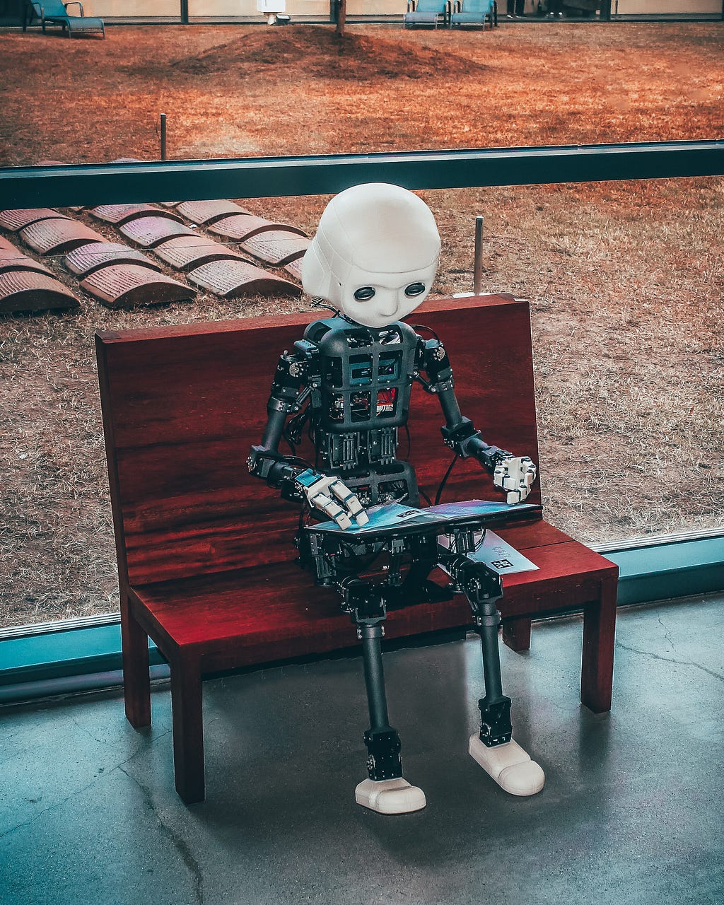 Robot works on a laptop overlooking a back yard scene