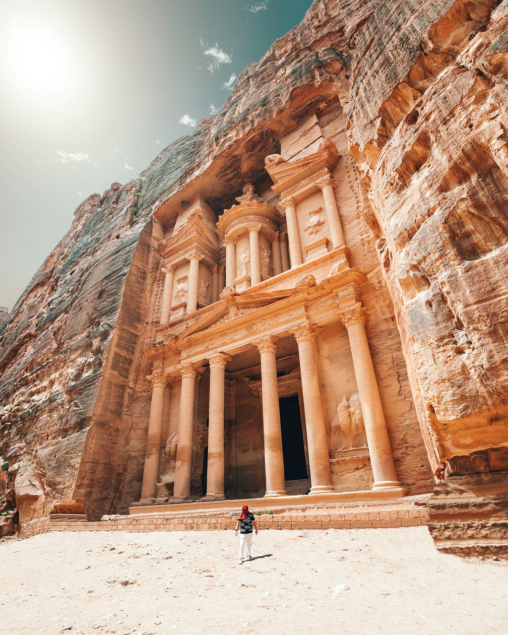 the Petra ruins, with a person standing alone in front of them