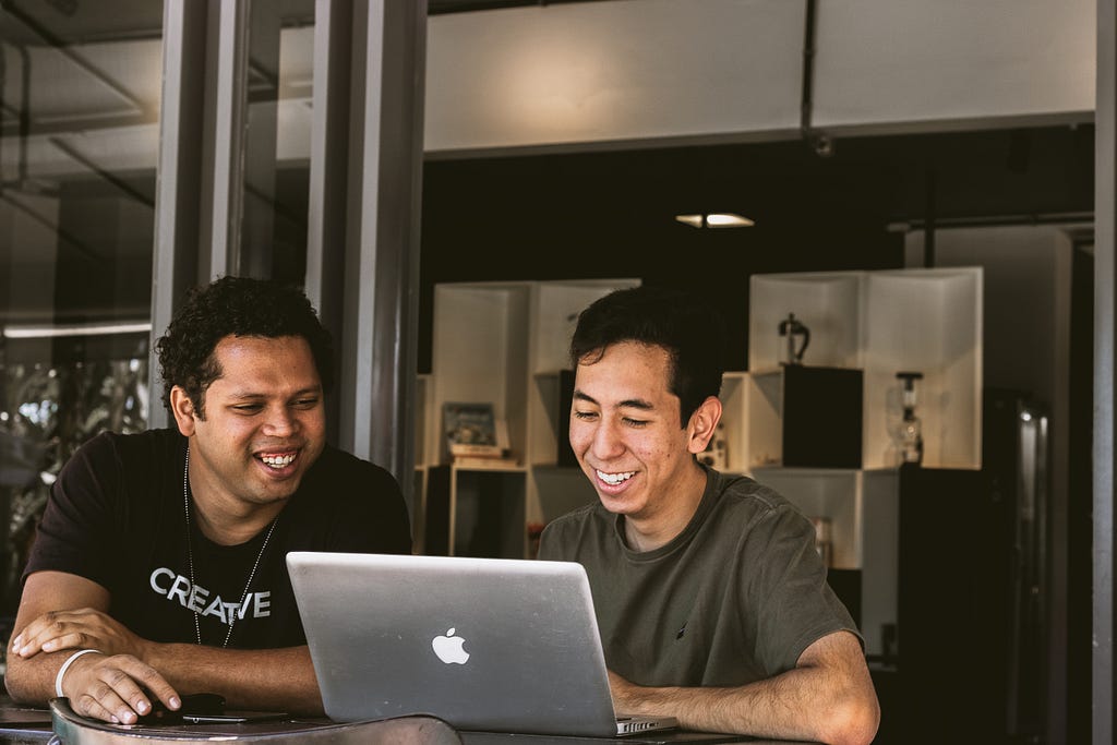 Two men looking at one laptop, smiling